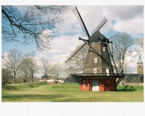 a windmill in a grassy field with Eastham Windmill in the background