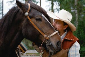 a man in a cowboy hat kissing a horse