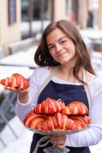 a woman holding a plate of croissants